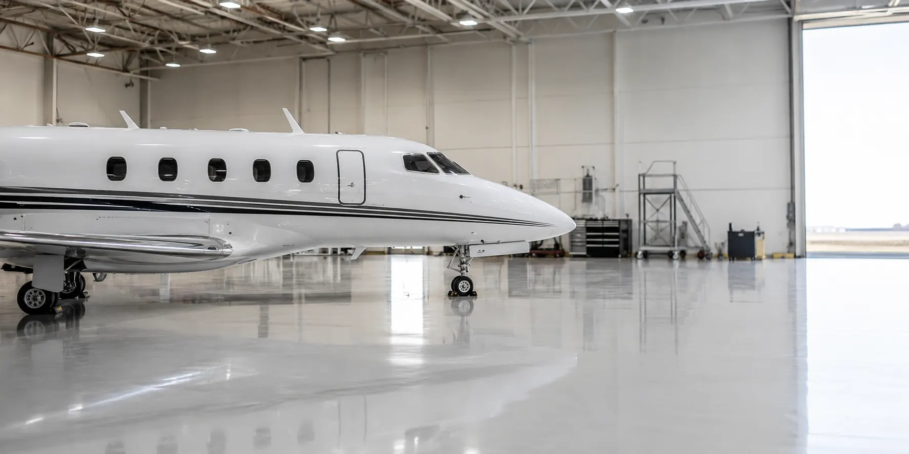 Side profile of a white business jet in a spotless hangar